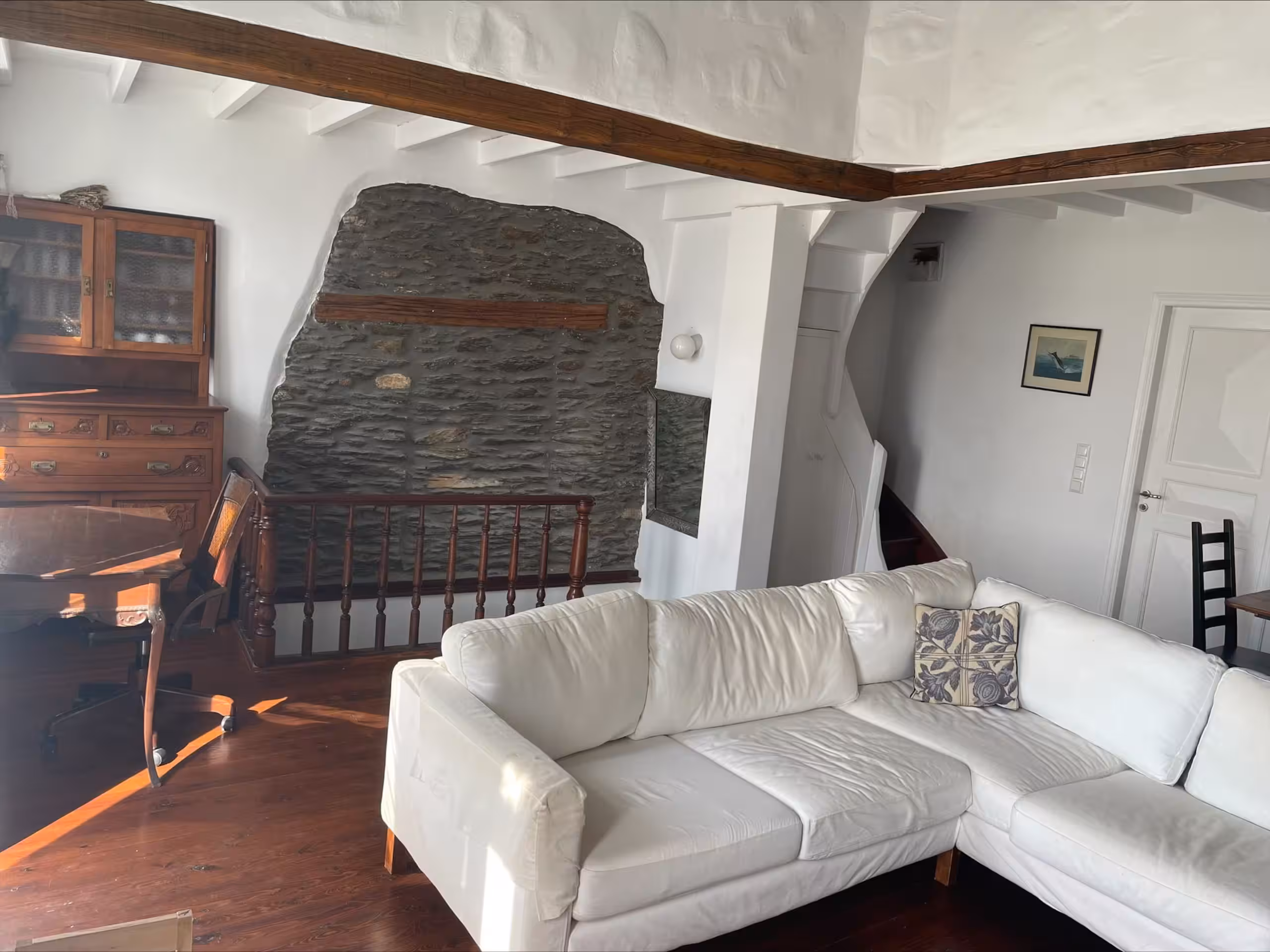 Main living room with white sofa and exposed stone